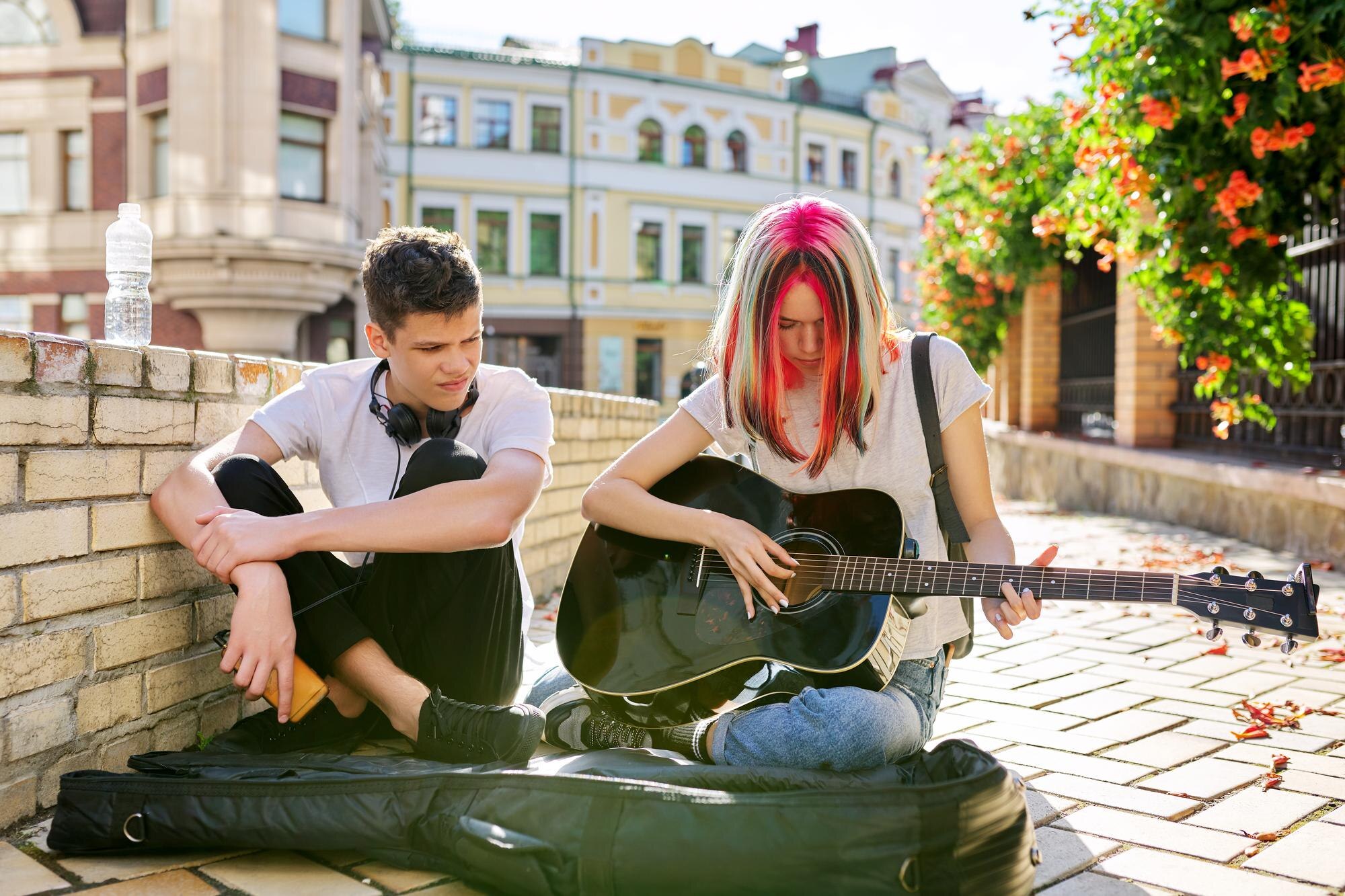 couple teenage hipsters street musicians making money by music girl with colored hair singing playin